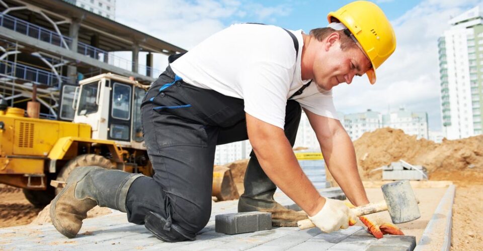 A man in construction gear is kneeling down