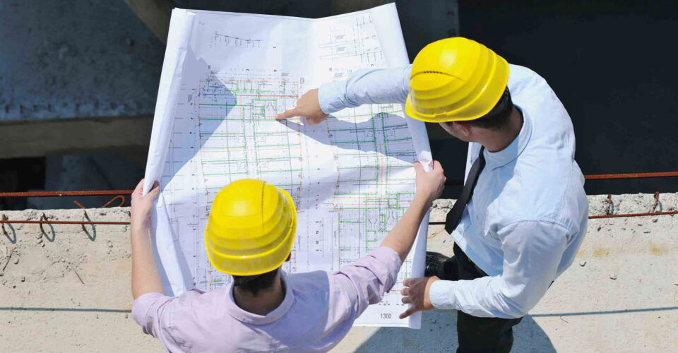 Two men in hard hats looking at a plan.