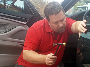 A man in red shirt holding a small hammer.