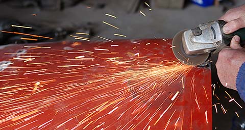 A person using an angle grinder to cut metal.