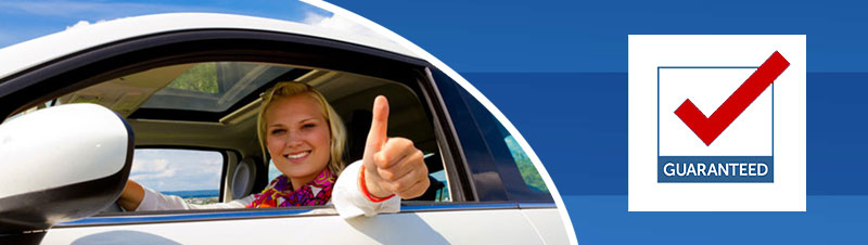 A little girl in the drivers seat of a car giving the peace sign.